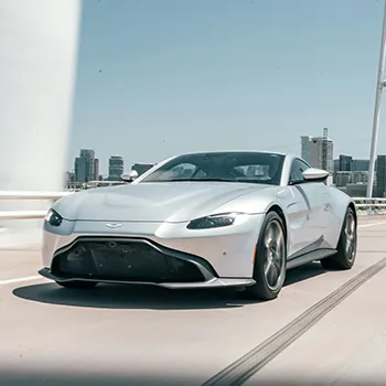 Silver sports car driving on urban bridge.