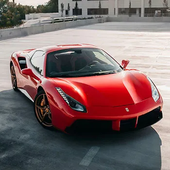 Red luxury sports car on rooftop parking lot.
