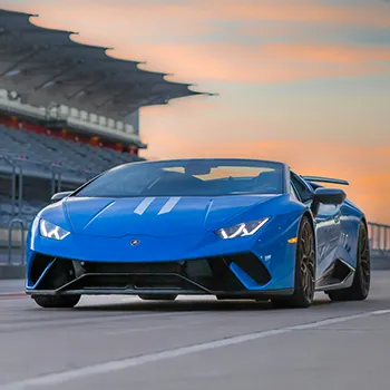 Blue sports car on racetrack at sunset.